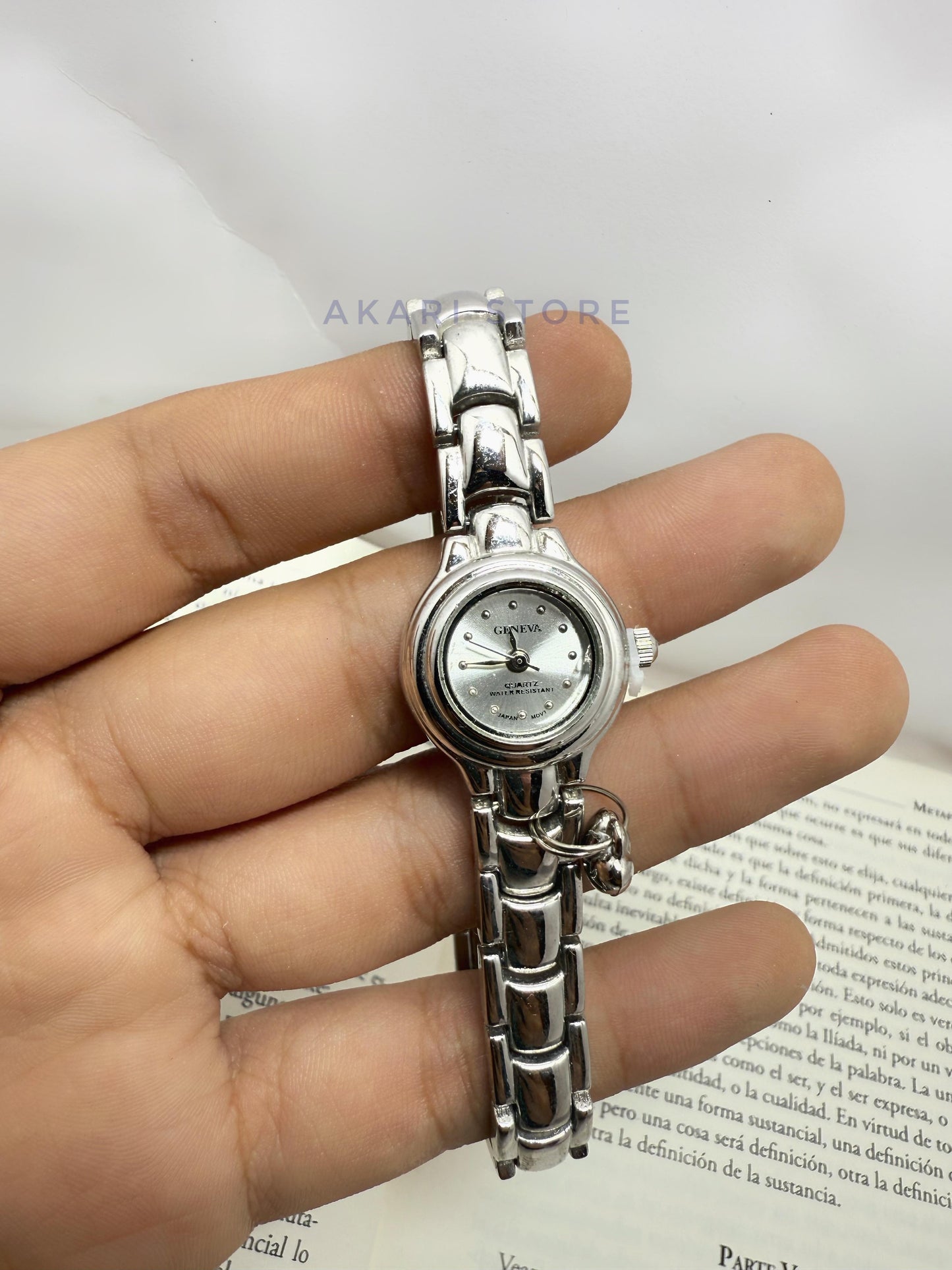 Reloj plateado circular con dije de corazón