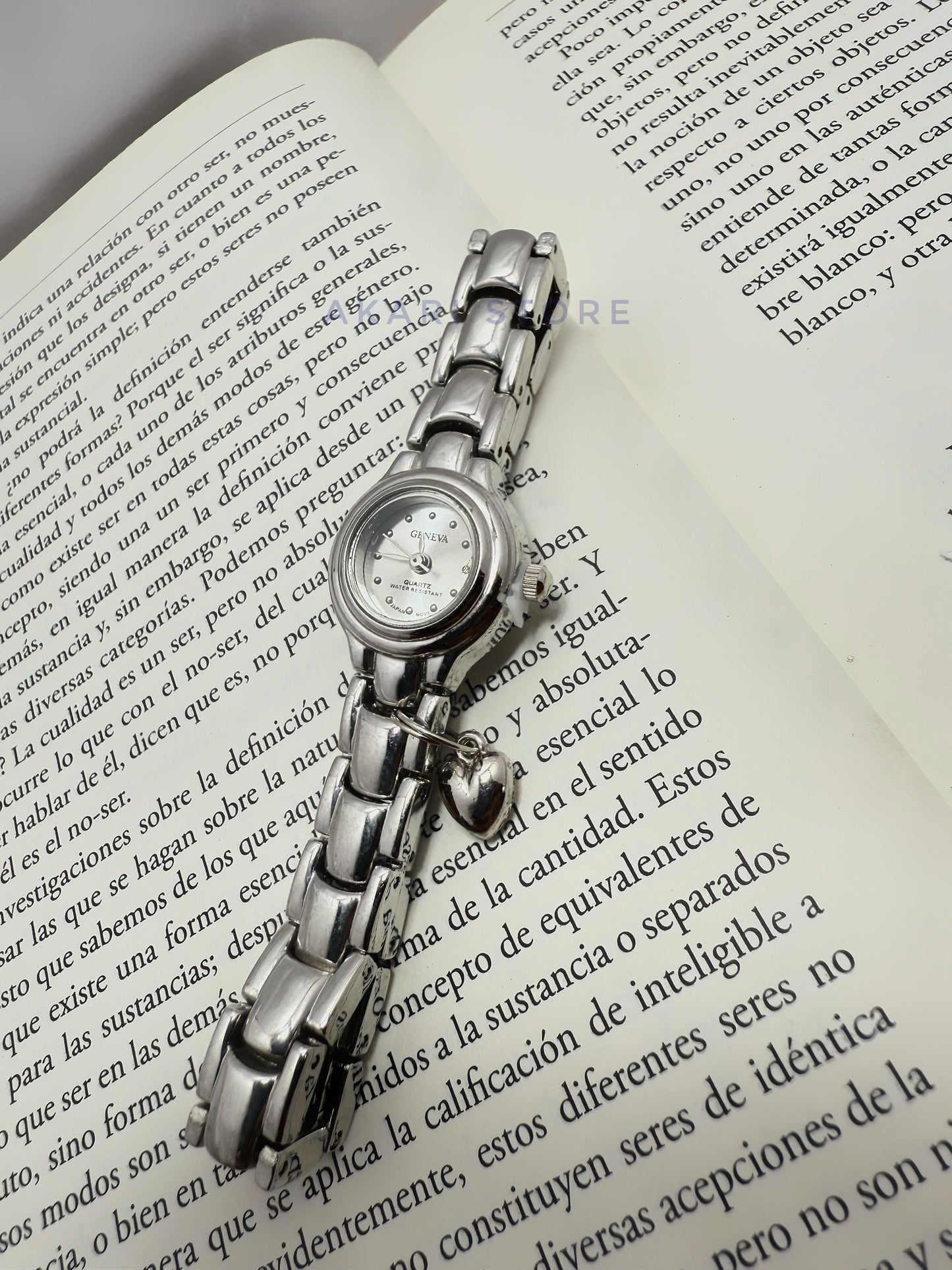 Reloj plateado circular con dije de corazón