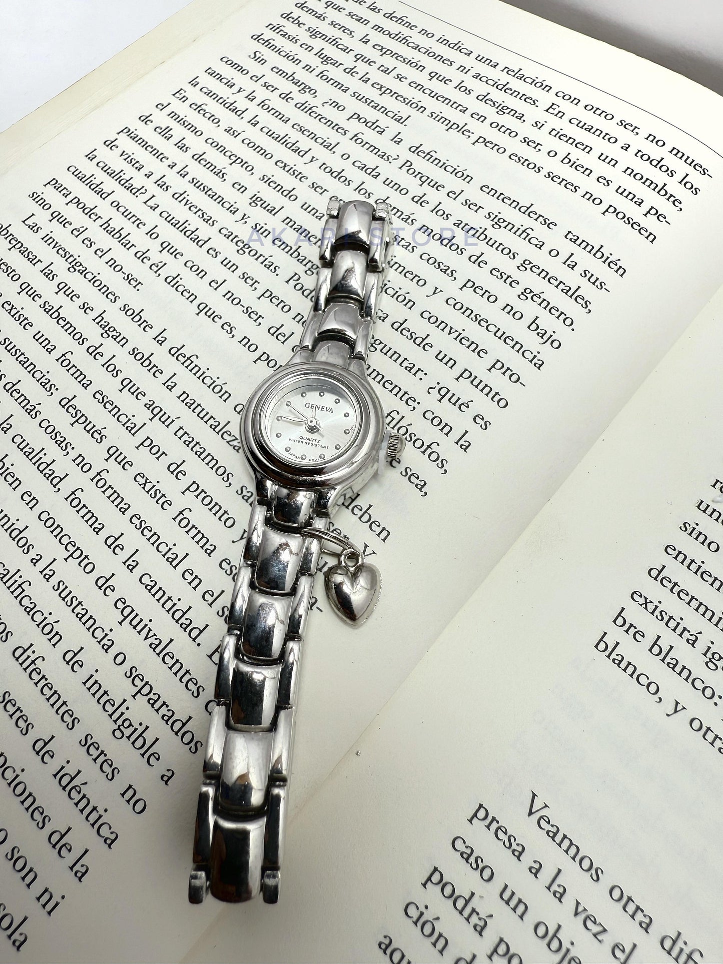 Reloj plateado circular con dije de corazón
