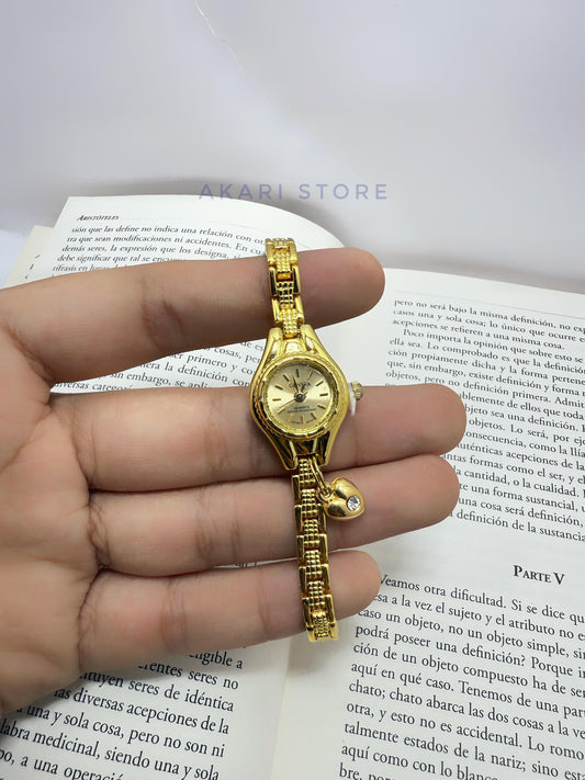 Reloj dorado con dije de corazón