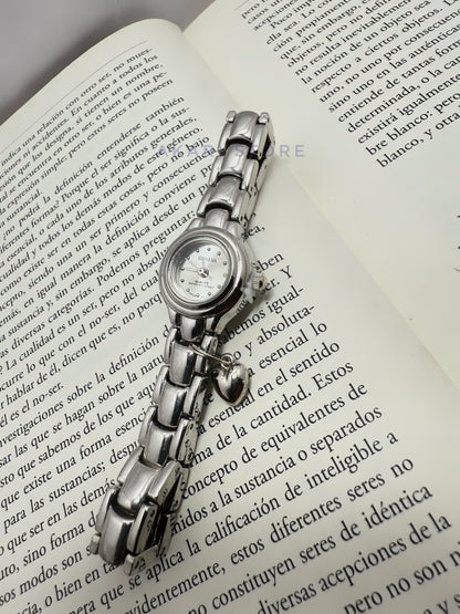 Reloj plateado circular con dije de corazón