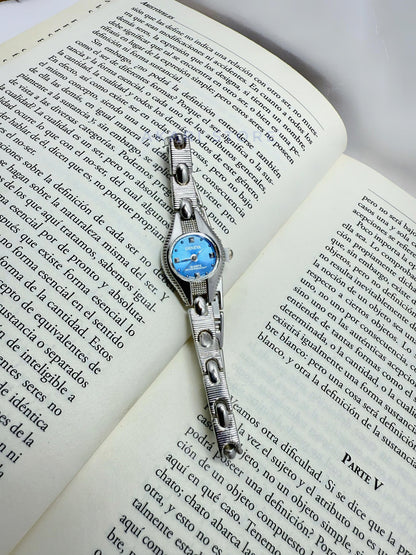 Reloj plateado con fondo azul
